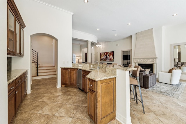 kitchen featuring a breakfast bar, a fireplace, sink, light stone counters, and kitchen peninsula