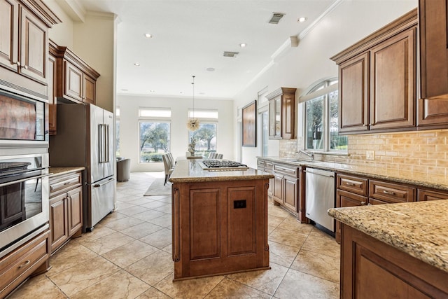 kitchen with hanging light fixtures, decorative backsplash, ornamental molding, and stainless steel appliances