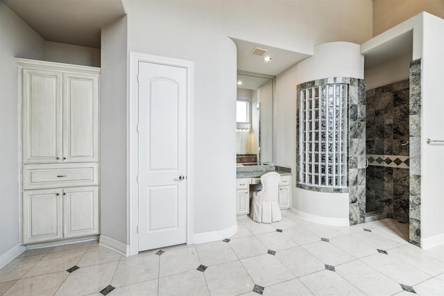 bathroom with tiled shower and tile patterned floors