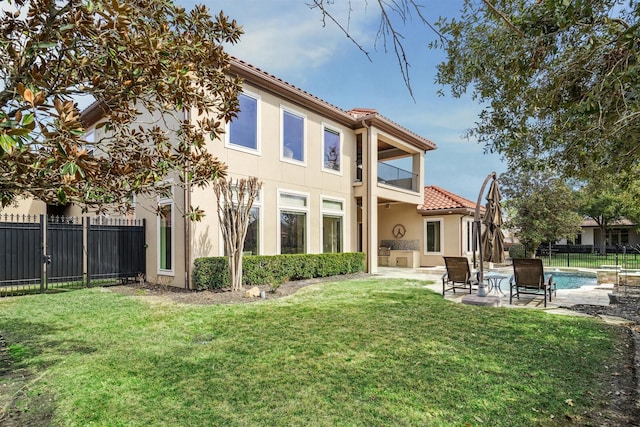 rear view of property featuring a yard, a patio area, and a balcony