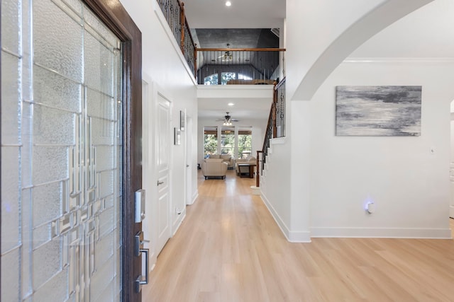 entryway with light hardwood / wood-style flooring, ornamental molding, and a high ceiling