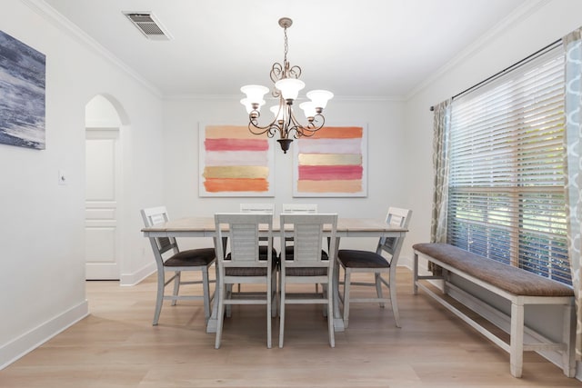 dining space with crown molding, an inviting chandelier, and light hardwood / wood-style flooring