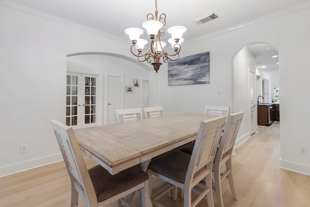 dining area featuring crown molding, sink, light wood-type flooring, and french doors