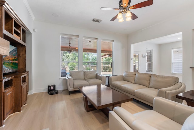 living room with ceiling fan, ornamental molding, a wealth of natural light, and light wood-type flooring