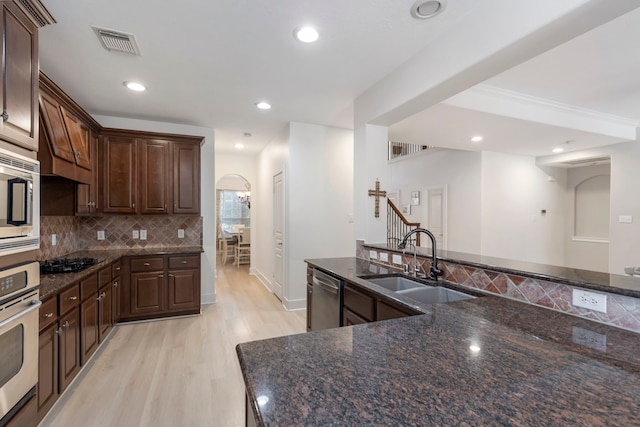 kitchen with dark brown cabinetry, appliances with stainless steel finishes, sink, and dark stone counters