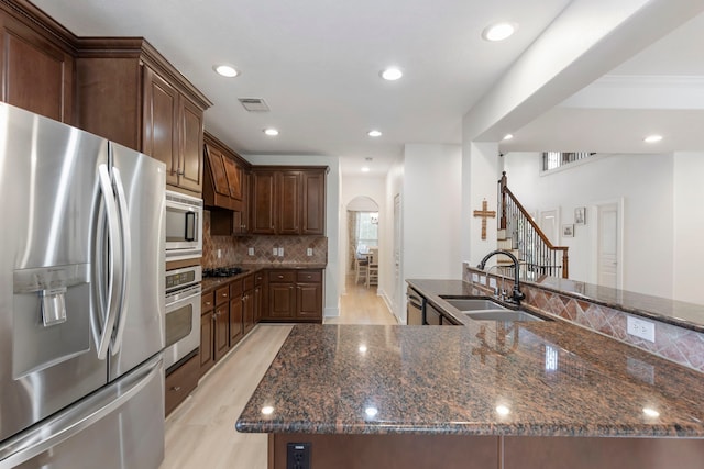 kitchen with dark stone countertops, sink, decorative backsplash, and stainless steel appliances