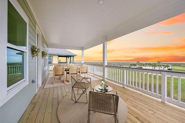 deck at dusk featuring a water view