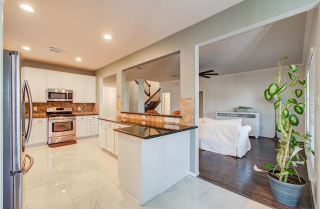 kitchen featuring white cabinetry, stainless steel appliances, kitchen peninsula, and decorative backsplash