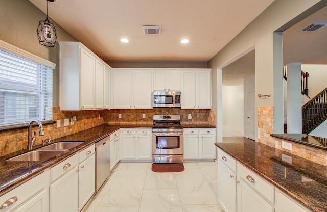 kitchen with dark stone countertops, sink, white cabinets, and appliances with stainless steel finishes