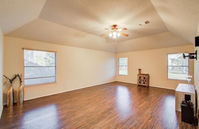 unfurnished living room featuring lofted ceiling, a textured ceiling, dark hardwood / wood-style floors, a tray ceiling, and ceiling fan