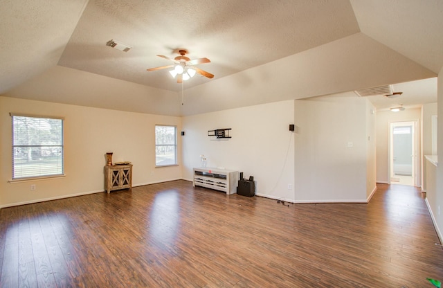 unfurnished living room with dark wood-type flooring, a textured ceiling, ceiling fan, and a tray ceiling