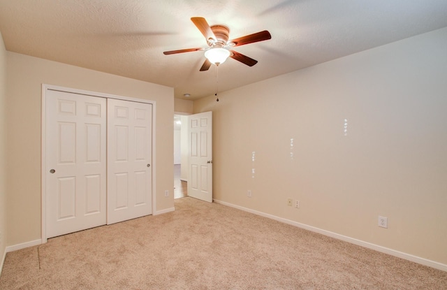 unfurnished bedroom with ceiling fan, light carpet, a textured ceiling, and a closet