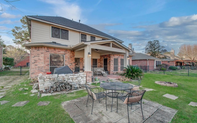 back of property featuring a patio, a lawn, ceiling fan, and a fire pit