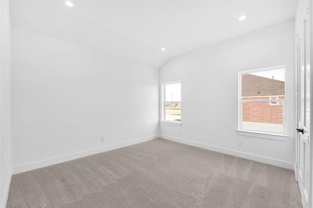 unfurnished room featuring lofted ceiling and light colored carpet