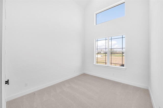 empty room with light carpet, plenty of natural light, and high vaulted ceiling