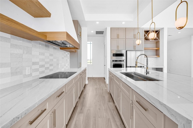 kitchen featuring black electric cooktop, decorative light fixtures, sink, and light stone counters