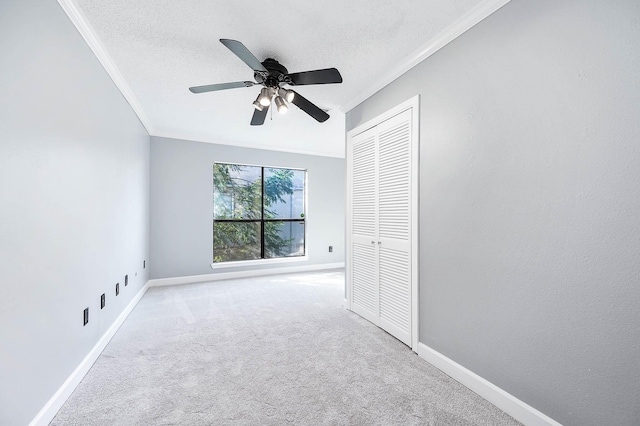 unfurnished bedroom featuring ceiling fan, carpet, ornamental molding, a textured ceiling, and a closet