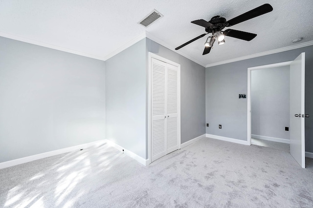 unfurnished bedroom with ornamental molding, light carpet, a textured ceiling, and a closet