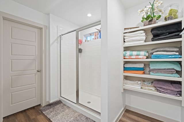 bathroom with a shower with door and hardwood / wood-style floors