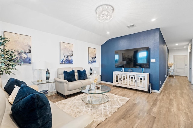 living room featuring lofted ceiling, a notable chandelier, and light wood-type flooring