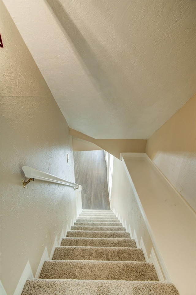 staircase with lofted ceiling and a textured ceiling