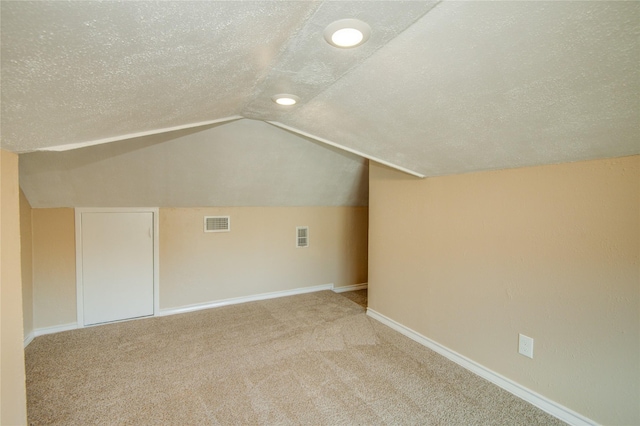 bonus room with lofted ceiling, carpet floors, and a textured ceiling