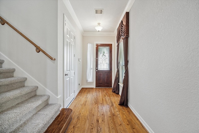 entryway with crown molding and light hardwood / wood-style floors