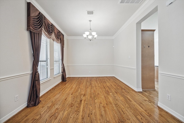 empty room featuring an inviting chandelier, ornamental molding, and light wood-type flooring