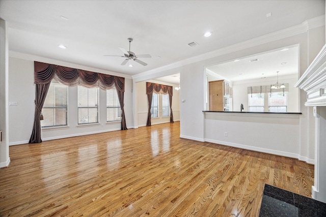 unfurnished living room featuring ornamental molding, sink, ceiling fan with notable chandelier, and light hardwood / wood-style flooring