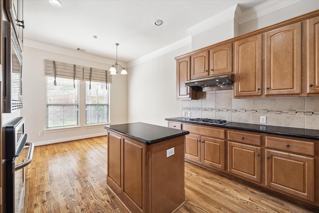 kitchen with backsplash, ornamental molding, light hardwood / wood-style floors, and a center island