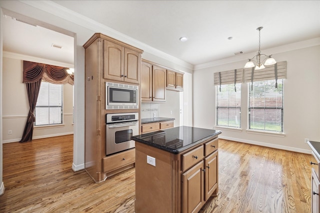 kitchen featuring a wealth of natural light, ornamental molding, dark stone counters, and appliances with stainless steel finishes