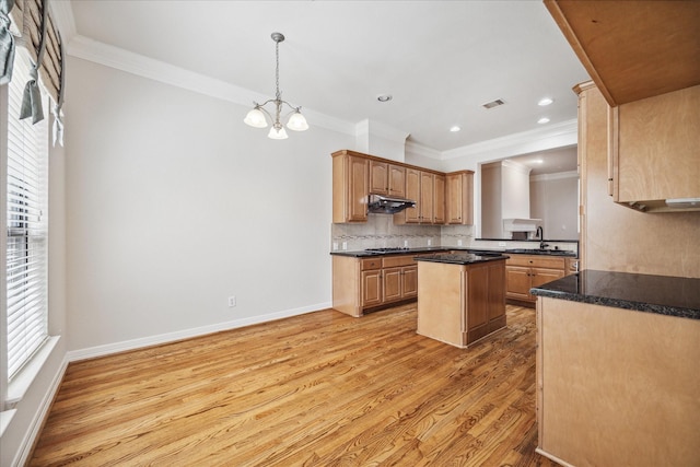 kitchen with decorative light fixtures, light hardwood / wood-style flooring, ornamental molding, a kitchen island, and backsplash