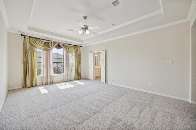 carpeted empty room featuring ornamental molding, ceiling fan, and a tray ceiling