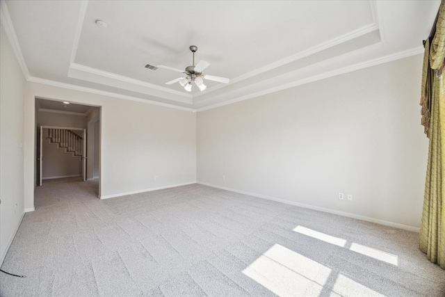 unfurnished bedroom featuring light carpet, a tray ceiling, crown molding, and ceiling fan