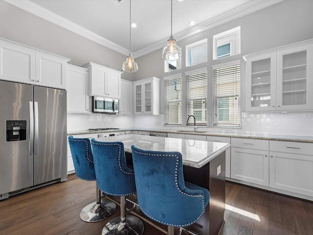 kitchen with appliances with stainless steel finishes, white cabinetry, crown molding, and a sink