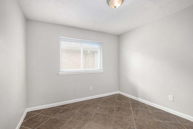 unfurnished room featuring dark tile patterned floors and a textured ceiling