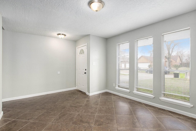 empty room with dark tile patterned flooring and a textured ceiling