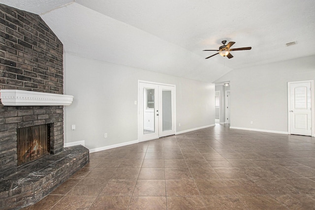 unfurnished living room featuring dark tile patterned floors, ceiling fan, a brick fireplace, vaulted ceiling, and french doors