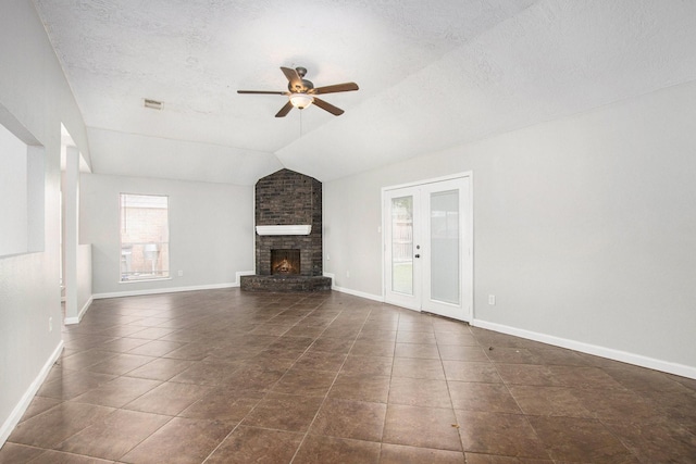 unfurnished living room with lofted ceiling, a textured ceiling, dark tile patterned floors, ceiling fan, and a fireplace