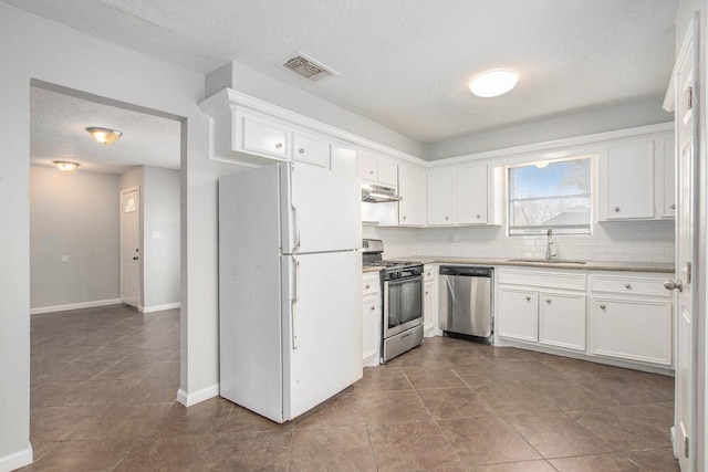 kitchen with sink, appliances with stainless steel finishes, white cabinetry, a textured ceiling, and decorative backsplash