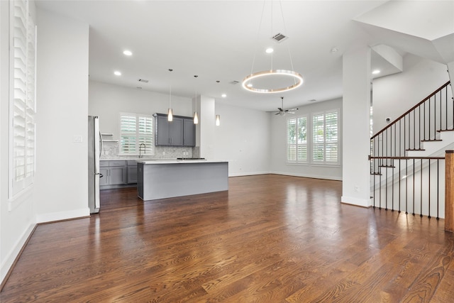 unfurnished living room featuring ceiling fan, dark hardwood / wood-style flooring, and sink