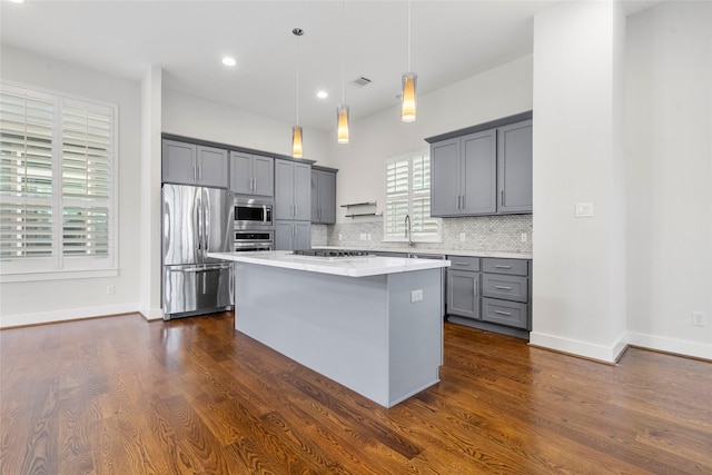 kitchen featuring decorative light fixtures, tasteful backsplash, sink, a center island, and stainless steel appliances