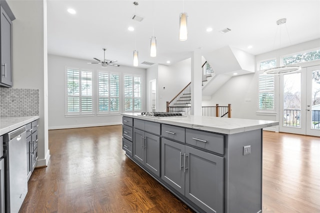 kitchen featuring pendant lighting, stainless steel appliances, a center island, and gray cabinetry