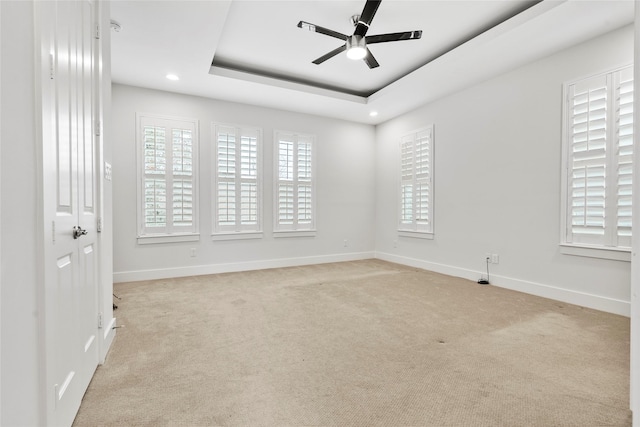 unfurnished room with light carpet, a raised ceiling, and ceiling fan