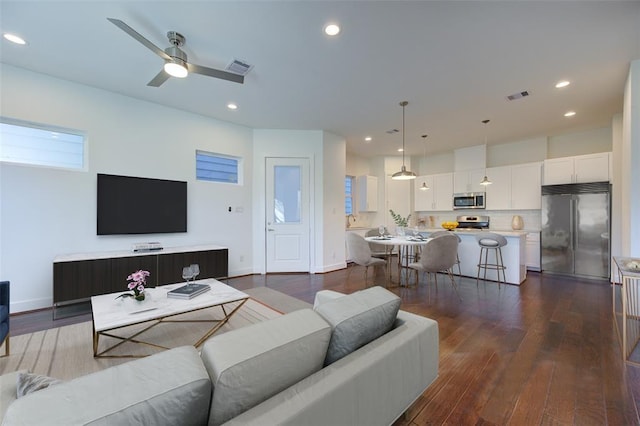 living room with ceiling fan, visible vents, dark wood-style flooring, and recessed lighting