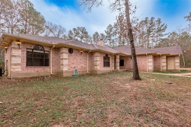 single story home featuring roof with shingles, brick siding, a chimney, and a front yard