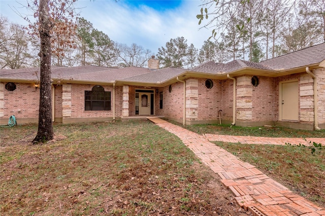 single story home featuring roof with shingles, brick siding, a chimney, and a front lawn