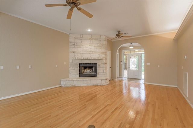 unfurnished living room with light wood-type flooring, baseboards, arched walkways, and crown molding