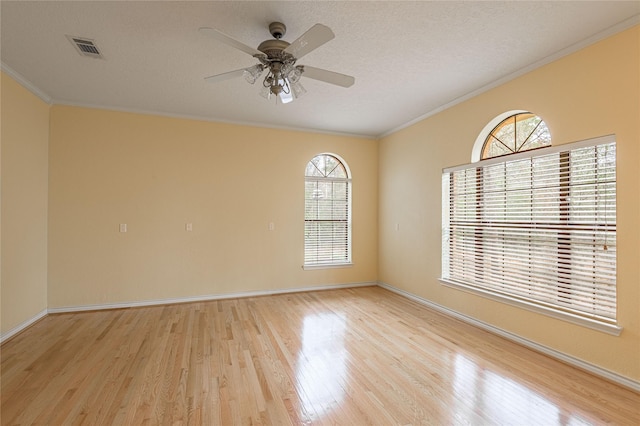 unfurnished room with light wood finished floors, baseboards, visible vents, a textured ceiling, and crown molding