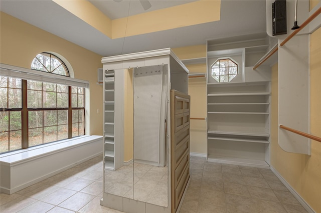 spacious closet featuring light tile patterned flooring, a raised ceiling, and a ceiling fan